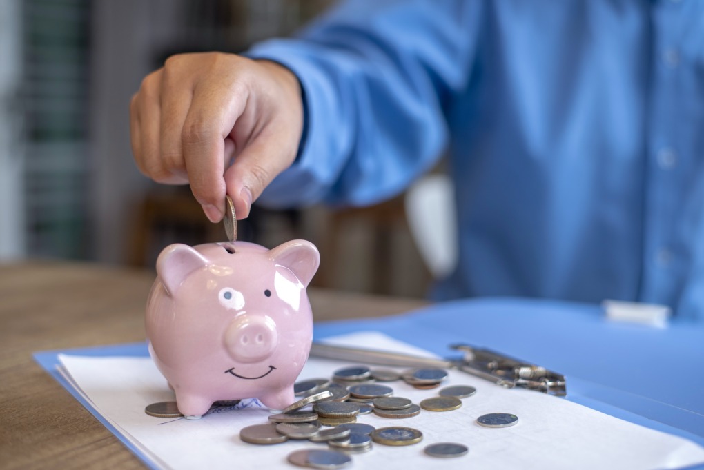 Một người đang bỏ tiền xu vào ống heo tiết kiệm. Ảnh: CNBC
